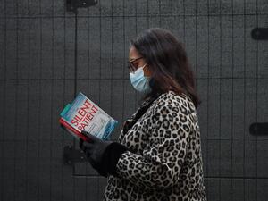 A woman reads a copy of the Silent Patient by author Alex Michaelides as she queues at an NHS Covid-19 vaccination centre for the Pfizer-BioNTech Covid-19 vaccine in London on December 30, 2020 as cases of the virus continue to soar and the Government raises restrictions around the country. Britain on December 30 became the first country in the world to approve AstraZeneca and Oxford University's low-cost Covid vaccine, raising hopes it will help tackle surging cases and ease pressure on creaking health ser