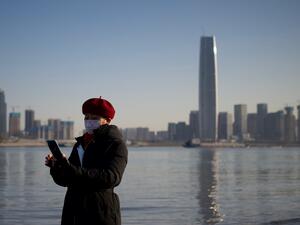 A woman uses her mobile phone along the banks of the Yangtze River on New Year's Eve day in Wuhan in China’s central Hubei province on December 31, 2020. Noel Celis / AFP