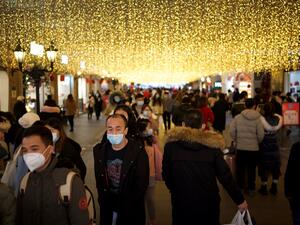 People wearing face masks walk along a shopping centre in Wuhan, in China’s central Hubei province on January 1, 2021. Noel Celis / AFP