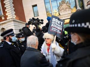 Police speak to a supporter of Wikileaks founder Julian Assange outside Westminster Magistrates court in London as he appears for a bail hearing on January 6, 2021. JUSTIN TALLIS / AFP