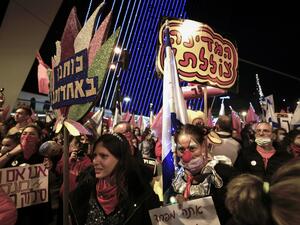 Israelis lift placards and flags as they take part in a demonstration against Prime Minister Benjamin Netanyahu at the entrance to the city in Jerusalem, amid the coronavirus pandemic crisis, on January 9, 2021. MENAHEM KAHANA / AFP