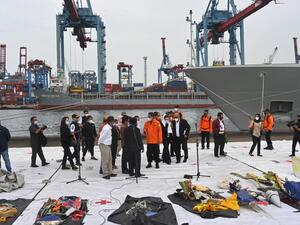 Members of the search and rescue teams and members of the Indonesian parliament look at pieces of wreckage from Sriwijaya Air flight SJ182 displayed at Tanjung Priok port, north of Jakarta, on January 11, 2021, after they were recovered during search operations off the coast for the Boeing 737-500 which crashed into the Java Sea minutes after takeoff on January 9. ADEK BERRY / AFP