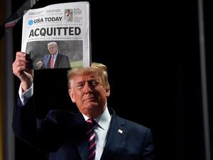 US President Donald Trump holds up a newspaper that displays a headline "Acquitted" as he arrives to speak at the 68th annual National Prayer Breakfast on February 6, 2020 in Washington,DC. President Donald Trump said Thursday that he suffered a "terrible ordeal" during his impeachment.  Nicholas Kamm / AFP
