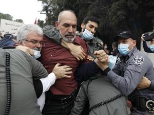 Israeli police detain a protester as Arab Israelis demonstrate on January 13, 2021 in the northern city of Nazareth against a plan by Prime Minister Benjamin Netanyahu to visit their city. Since July, thousands of Israelis have rallied each week to protest against the prime minister and the economic fallout from the pandemic. Ahmad GHARABLI / AFP