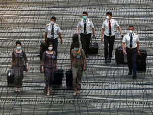 Singapore Airlines crew member walk along the transit hall of Changi International Airport terminal in Singapore on January 14, 2021. Roslan RAHMAN / AFP