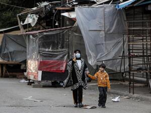 A mask-clad woman and boy walk past shuttered shops and stalls in Souk Sabra in the southern suburbs of the Lebanon's capital Beirut on January 16, 2021, despite a national total lockdown as a measure against the COVID-19 coronavirus pandemic. ANWAR AMRO / AFP