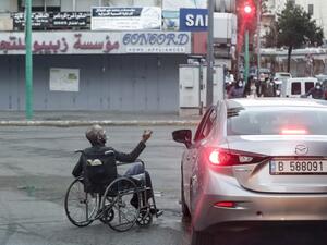 A wheelchair-bound beggar is seen next to a car stopping at a red light, in Lebanon's capital Beirut on January 16, 2021, despite a total lockdown due to the COVID-19 coronavirus pandemic. ANWAR AMRO / AFP