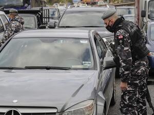 A member of the Lebanese security forces checks a citizen's documents at a COVID-19 checkpoint near the coastal town of Safra on the Tripoli-Beirut main highway on January 19, 2021, as Lebanon enters a second week under lockdown aimed at preventing the country's creaking healthcare system from collapsing. JOSEPH EID / AFP