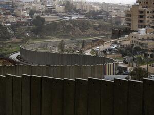 A picture taken on January 20, 2021 shows the Israeli settlement of Pisgat Zeev (L), built in a suburb of the mostly Arab east Jerusalem, and the Palestinian Shuafat refugee camp (R) behind Israel's controversial separation wall. AHMAD GHARABLI / AFP