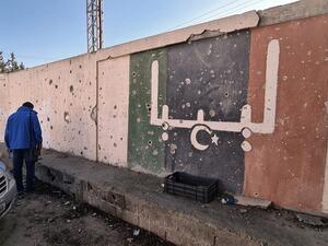 In this file photo taken on November 19, 2020, a Libyan stands in front of a school, which was damaged during fighting between rival factions, in the capital Tripoli's suburb of Ain Zara. The writing on the wall reads "Libya" in Arabic. Foreign forces ignored a deadline to pull out of Libya as scheduled Saturday under a UN-backed ceasefire deal, highlighting the fragility of peace efforts after a decade of conflict. Mahmud TURKIA / AFP