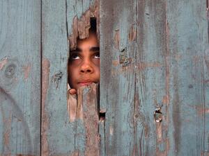 A Palestinian girl peeps from a hole at her house's gate in Beit Hanun in the northern Gaza Strip on January 25, 2021. Mohammed ABED / AFP
