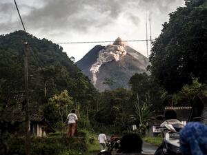People look up at Mount Merapi, Indonesia's most active volcano, as it spews rocks and ash out for another day in Yogyakarta on January 27, 2021. Agung Supriyanto / AFP