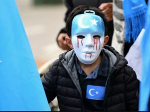 A boy wearing a blue mask with tears of blood takes part in a protest march of ethnic Uighurs, in Brussels on April 27, 2018, asking for the European Union to call upon China to respect human rights. (Emmanuel Dunand, AFP)