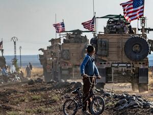  A Syrian boy on a bicycle watched a convoy of US armored vehicles drive away on a dirt road in northeastern Syria. Delil Souleiman (AFP via Getty Image File Photo)