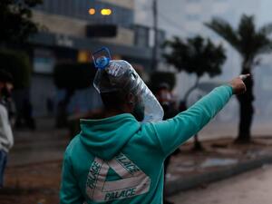 A Lebanese anti-government protester wearing a water bottle as a shield points during clashes with security forces in front of the Serail (headquarters of the Governorate), in the northern port city of Tripoli, following a demonstration to protest against the economic situation, on January 28, 2021. Tripoli was already one of Lebanon's poorest areas before the coronavirus pandemic piled new misery onto a chronic economic crisis. Many of its residents have been left without an income since Lebanon imposed a 