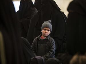 A boy sits among women awaiting departure during the release of another group of Syrian families from the Kurdish-run al-Hol camp which holds suspected relatives of Islamic State (IS) group fighters, in Hasakeh governorate in northeastern Syria, on January 28, 2021. Delil SOULEIMAN / AFP