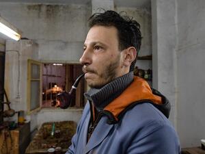 Anis Bouchnak tries a briar wood pipe that he made at his workshop in the northwestern Tunisian coastal town of Tabarka, on January 28, 2021. Bouchnak, 37, who in 2011 took over the family business started by his grandfather, is the only craftsman in Tunisia, and one of the few in the region, to continue to make pipes by hand. FETHI BELAID / AFP