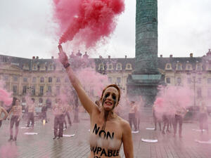A Femen activist, with "not guilty" written on the chest, lights flares during a protest against sexism in the French judicial system at the Vendôme square in Paris on February 6, 2021. Alain JOCARD / AFP