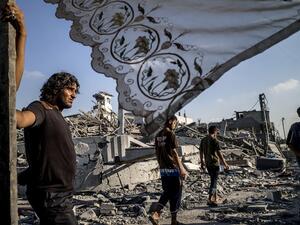 In this file photo taken on August 6, 2014 Palestinians stand next to a makeshift shelter erected outside their destroyed house in the devastated neighbourhood of Shejaiya in Gaza City. MARCO LONGARI / AFP