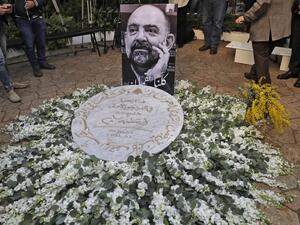 A memorial plaque is placed upon a flower arrangement as friends and family members of slain prominent Lebanese activist and intellectual Lokman Slim (image), attend a memorial ceremony in the garden of the family residence in the capital Beirut's southern suburbs, a week after he was found dead in his car, on February 11, 2021. Slim, found shot dead in southern Lebanon last week at age 58, was an outspoken critic of the Shiite movement Hezbollah and an advocate for preserving the memory of his country's ci