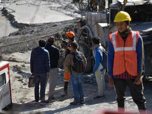 Defence research and development organisation (DRDO) scientists talk with an emergency and rescue official (in orange cap) after arriving near Tapovan tunnel, where dozens are still feared to be trapped, during rescue operations in Tapovan of Chamoli district on February 12, 2021 following a flash flood thought to have been caused when a glacier burst on February 7. Virender SINGH NEGI / AFP