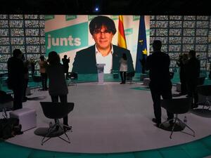 Attendees applaud as a screen displays images of former Catalan president Carles Puigdemont during "Junts per Catalunya" party (Together For Catalonia) closing campaign meeting for the up-coming Catalonia regional elections in Barcelona on February 12, 2021. More than three years after a failed bid to break away from Spain, Catalonia goes to the polls on February 14, 2021 for an election that Madrid hopes will unseat the region's ruling separatists.  LLUIS GENE / AFP