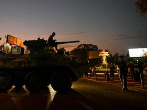 People gather around an armoured vehicle maneuvering on a city street, following days of mass protests against the military coup, in Yangon on February 14, 2021. SAI AUNG MAIN / AFP