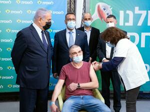Israeli Prime Minister Netanyahu (L) stands by the 4,000,000th person to be vaccinated at Leumit Health Care Services vaccination facility in Jerusalem on February 16, 2021. Israel's largest healthcare provider said a study of more than half a million fully vaccinated Israelis indicated the Pfizer/BioNTech jab gave 94 percent protection against Covid-19. Alex KOLOMIENSKY / POOL / AFP