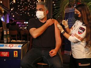 A health worker administers the COVID-19 vaccine to an Israeli at a bar in the coastal city of Tel Aviv on February 18, 2021. GIL COHEN-MAGEN / AFP