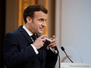 French President Emmanuel Macron removes his protective face mask as he attends the 2021 Munich Security Conference held by video link at the Elysee Palace in Paris on February 19, 2021 amidst the coronavirus disease (Covid-19) outbreak. BENOIT TESSIER / POOL / AFP