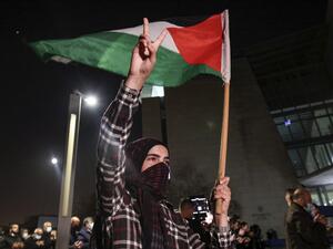 A demonstrator raises a hand with the victory gesture while holding a Palestinian flag outside the Haifa District Court in Israel's northern Mediterranean coastal city on February 27, 2021, during a protest by Arab Israelis against violence against their community and in solidarity with protesters that were arrested the previous day in Umm al-Fahem. AHMAD GHARABLI / AFP