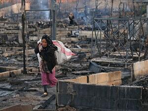 Syrian refugees salvaging her belongings from a camp set on fire!