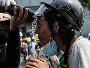 A protester seeks to keep the tear gas away