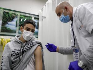 A health worker administers a dose of the Pfizer-BioNtech COVID-19 vaccine on a man 