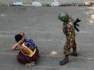 A soldier stands next to a detained man 