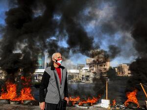 A man wearing a cross necklace and clad in mask depicting the Lebanese flag 