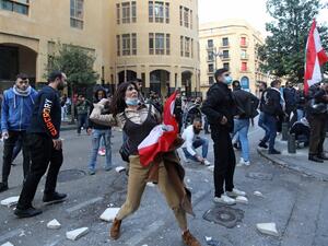 A Lebanese demonstrator hurls rocks over a fortified gate