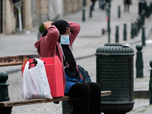 Woman on a bench adjusts her mask
