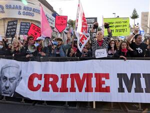 Protesters, one wearing a mask depicting Israeli Prime Minister Benjamin Netanyahu
