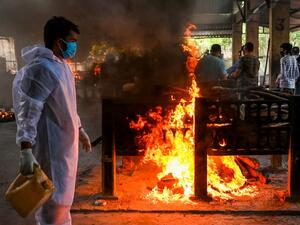 A crematorium staff lights a pyre of a Covid-19 coronavirus victim