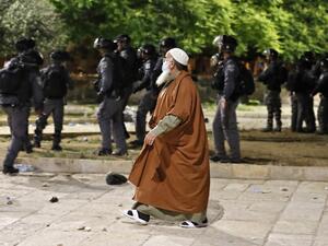 A Palestinian man walks amid the clashes between Israeli police and Palestinian protesters at al-Aqsa mosque compound in Jerusalem