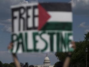 An activist holds up a sign with the US Capitol in the background, in support of Palestine, near the Washington monument in Washington, DC on May 15, 2021. US President Joe Biden, in a phone call with Israeli Prime Minister Benjamin Netanyahu, expressed his "grave concern" Saturday over the flareup of violence in Israel and Gaza, the White House announced