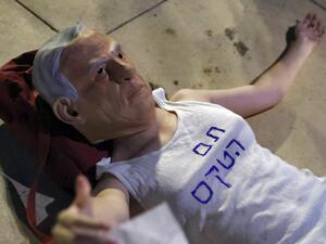 An Israeli protester wears a mask of Prime Minister Benjamin Netanyahu and a T-shirt with a slogan reading in Hebrew: "the ceremony is over", during a demonstration to support the opposition for the formation of a government, on May 31, 2021, in Tel Aviv. Israeli opposition leader Yair Lapid today said many obstacles remain before a diverse coalition can be built to oust veteran Prime Minister Netanyahu, but voiced hope it will achieve the "greater goal"
