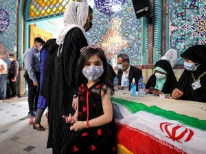 A girl looks on as a woman registers to vote at a polling station polling station in Iran's capital Tehran on June 18, 2021, during the 2021 presidential election. Iranians voted on June 18 in a presidential election in which ultraconservative cleric Ebrahim Raisi is seen as all but certain to coast to victory after all serious rivals were barred from running