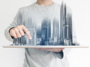 a man using digital tablet, and modern buildings hologram