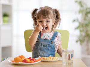 Cute child little girl eating healthy food in kindergarten