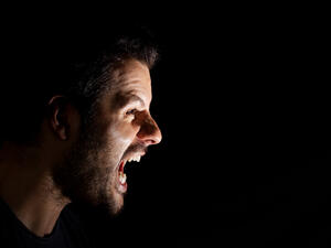 Angry man shouting out loud isolated on black background.