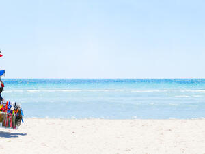  Peddler with many hats on their heads and other items for sale.