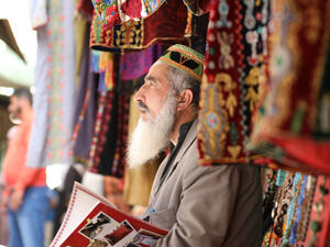 An old man, white hair, works in the market in and reads a book. Palestine, Hebron