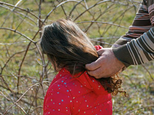 Man's hands on the hair of a little girl